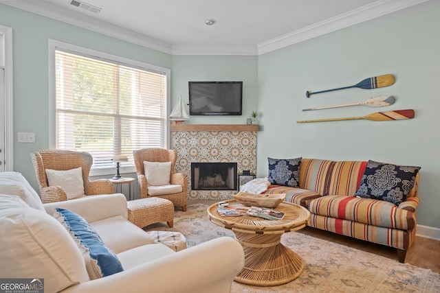 living room featuring a tile fireplace, crown molding, and hardwood / wood-style floors