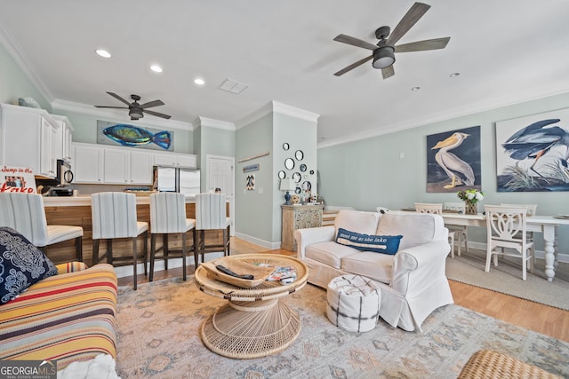 living room with ornamental molding, ceiling fan, and light hardwood / wood-style flooring