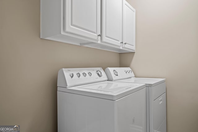 clothes washing area featuring cabinets and washer and dryer