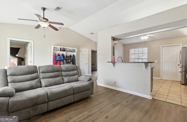 living room featuring lofted ceiling, sink, ceiling fan, and light hardwood / wood-style floors