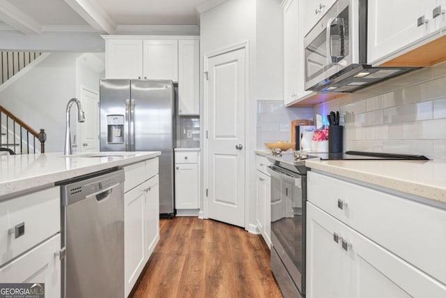 kitchen with stainless steel appliances, ornamental molding, white cabinets, and light stone counters