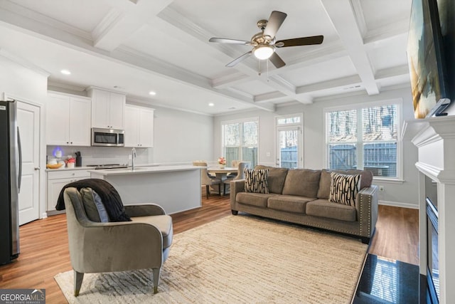 living room featuring beamed ceiling, coffered ceiling, and light wood-type flooring