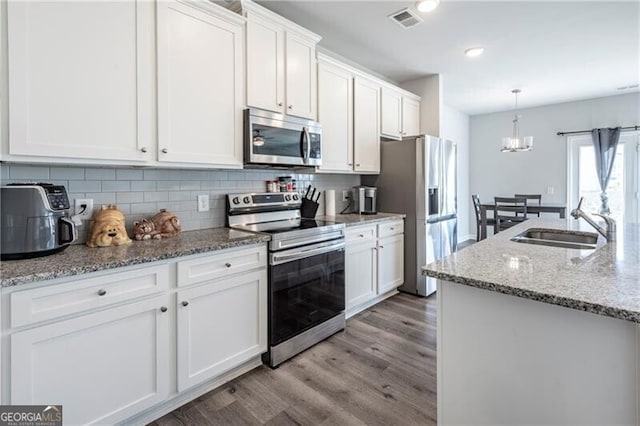 kitchen featuring sink, stainless steel appliances, white cabinets, and light stone countertops