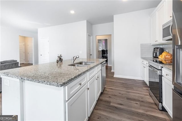 kitchen with sink, white cabinets, stainless steel appliances, light stone countertops, and a center island with sink