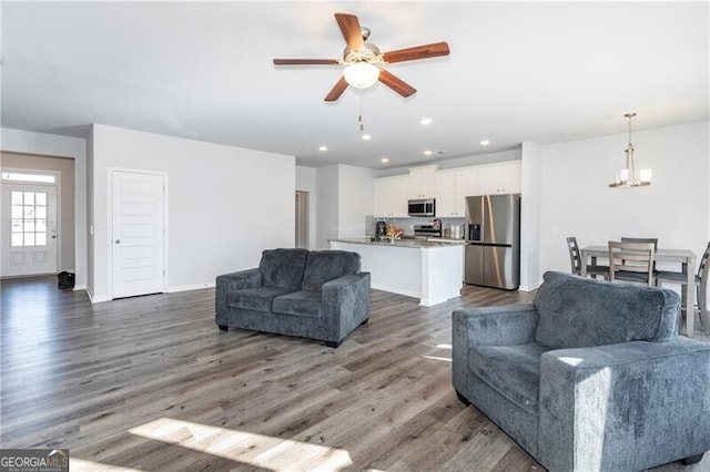 living room featuring dark hardwood / wood-style flooring and ceiling fan with notable chandelier