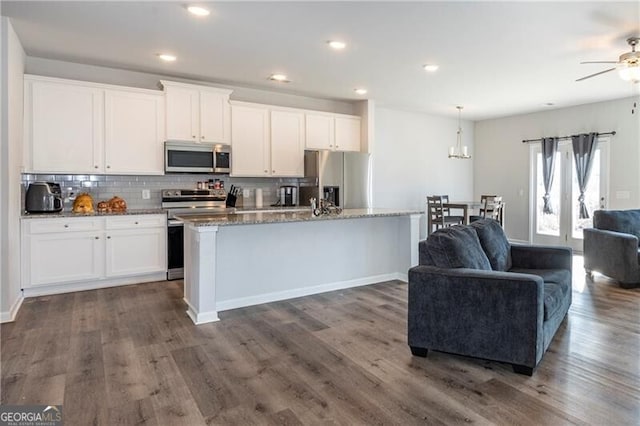 kitchen with white cabinetry, appliances with stainless steel finishes, light stone counters, and a center island with sink