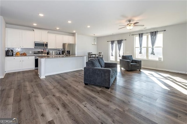 kitchen with white cabinetry, dark hardwood / wood-style flooring, stainless steel appliances, a kitchen island with sink, and decorative backsplash