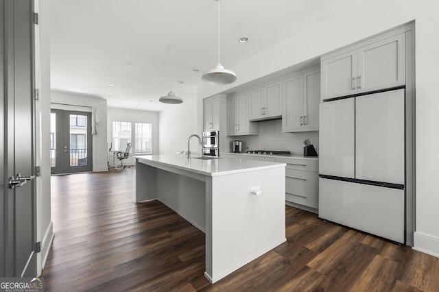 kitchen with gray cabinetry, dark hardwood / wood-style floors, an island with sink, stainless steel appliances, and decorative backsplash