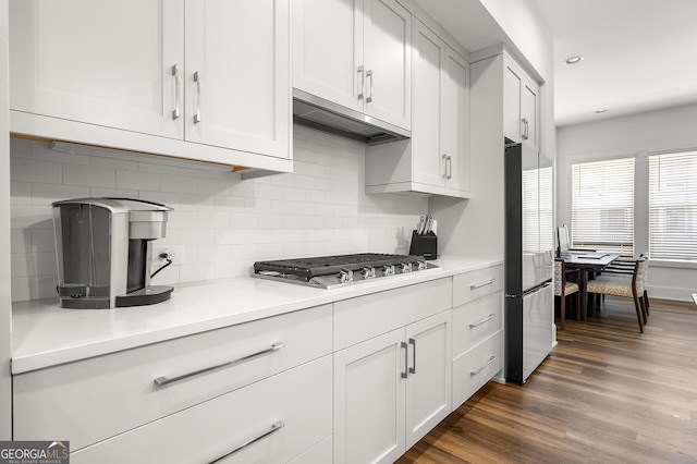 kitchen featuring white cabinetry, backsplash, stainless steel appliances, dark hardwood / wood-style flooring, and exhaust hood