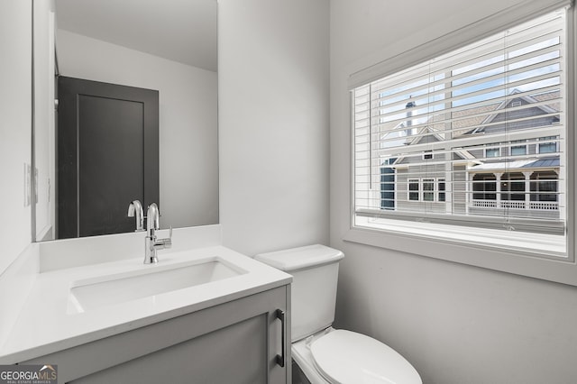 bathroom featuring plenty of natural light, toilet, and vanity