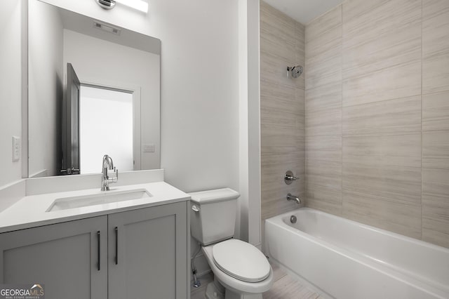 full bathroom with tiled shower / bath, vanity, and toilet