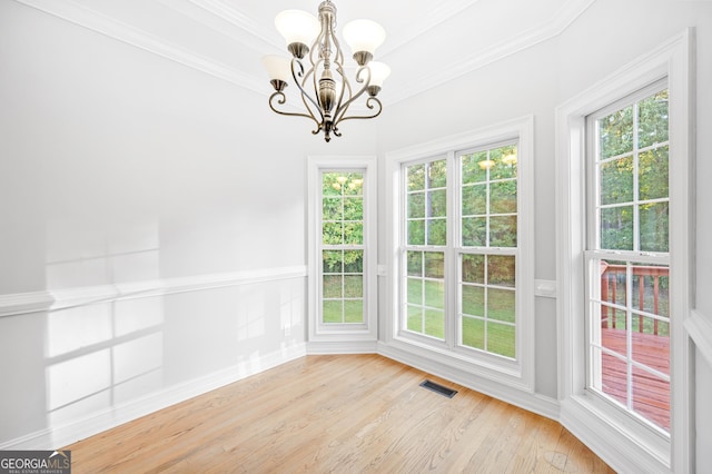 unfurnished dining area with ornamental molding, a chandelier, and light wood-type flooring