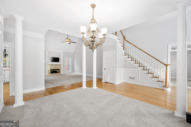 unfurnished living room featuring decorative columns, ornamental molding, light carpet, and ceiling fan