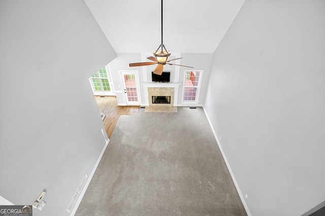 unfurnished living room with lofted ceiling, light carpet, and ceiling fan