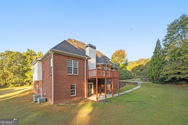 back of property with a wooden deck, a yard, central AC, and a patio