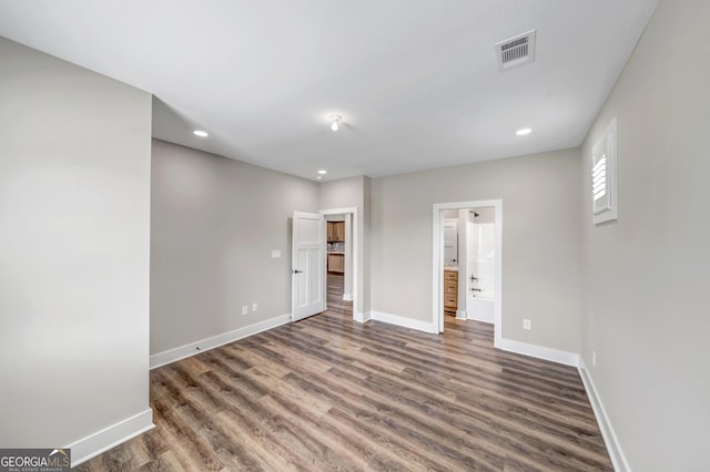 unfurnished bedroom featuring ensuite bathroom and dark hardwood / wood-style flooring