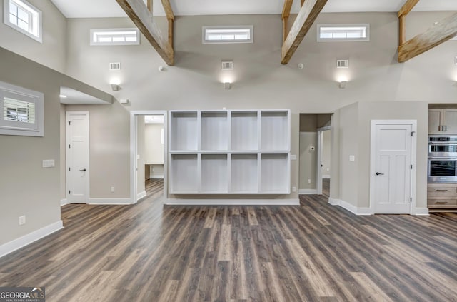 unfurnished living room with a towering ceiling and dark hardwood / wood-style flooring