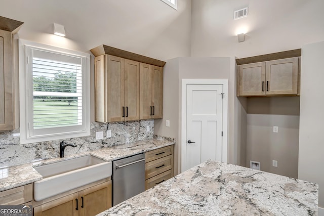 kitchen featuring light brown cabinetry, sink, tasteful backsplash, light stone counters, and stainless steel dishwasher