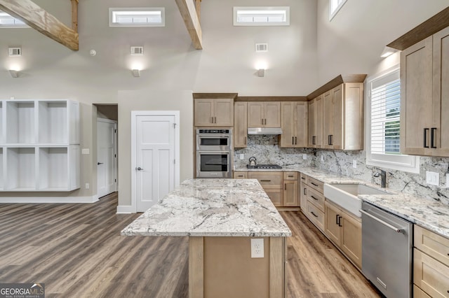 kitchen featuring sink, appliances with stainless steel finishes, light stone counters, a kitchen island, and light brown cabinetry