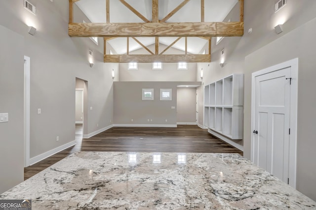 spare room featuring beamed ceiling, dark wood-type flooring, and high vaulted ceiling