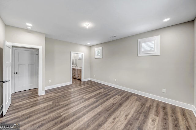 unfurnished bedroom featuring dark hardwood / wood-style flooring and connected bathroom