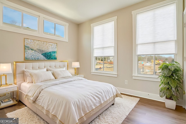 bedroom with multiple windows and dark hardwood / wood-style flooring