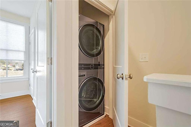 laundry area featuring wood-type flooring and stacked washer and clothes dryer