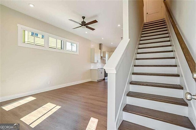 stairs with hardwood / wood-style floors and ceiling fan