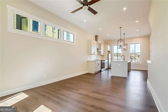 unfurnished living room featuring dark wood-type flooring, ceiling fan, and sink