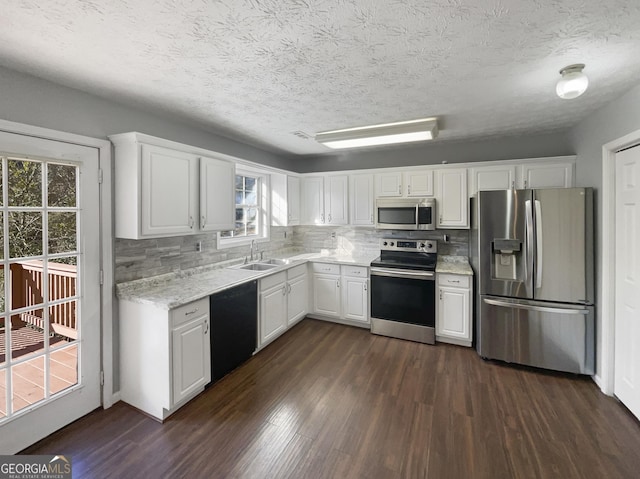 kitchen featuring sink, dark wood-type flooring, appliances with stainless steel finishes, white cabinetry, and decorative backsplash