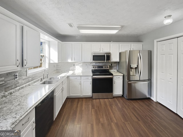 kitchen featuring appliances with stainless steel finishes, dark hardwood / wood-style floors, sink, white cabinets, and decorative backsplash