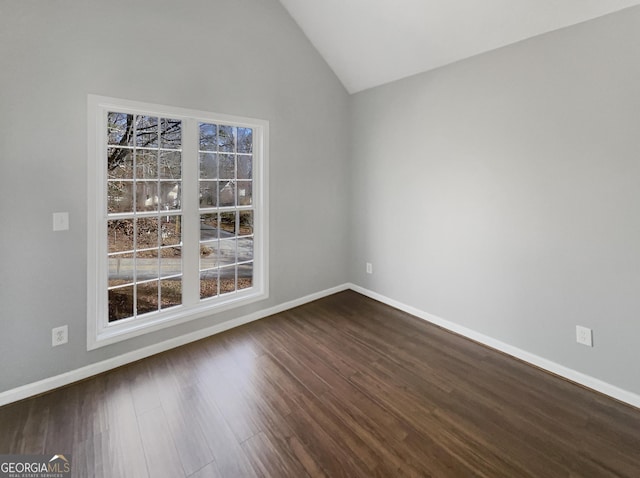 spare room with vaulted ceiling, plenty of natural light, and dark hardwood / wood-style flooring