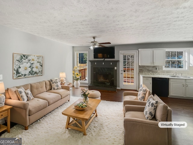 living room featuring sink, wood-type flooring, a premium fireplace, and ceiling fan