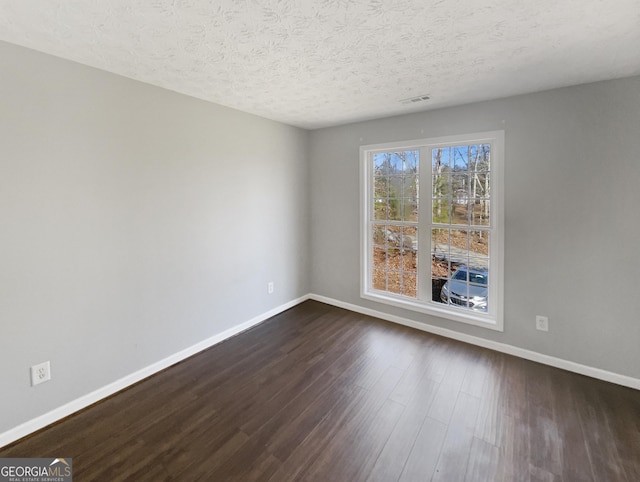 empty room featuring dark wood-type flooring and a textured ceiling