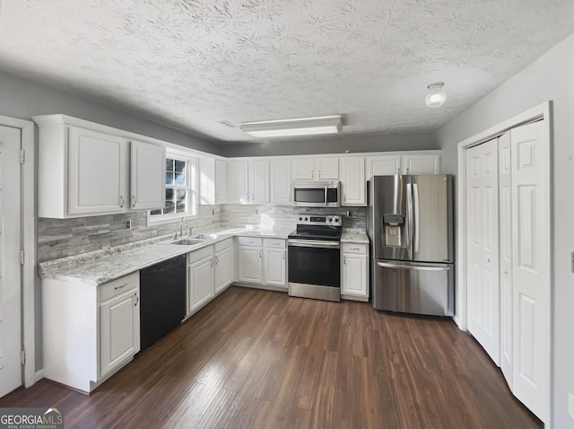 kitchen with stainless steel appliances, sink, dark wood-type flooring, and white cabinets