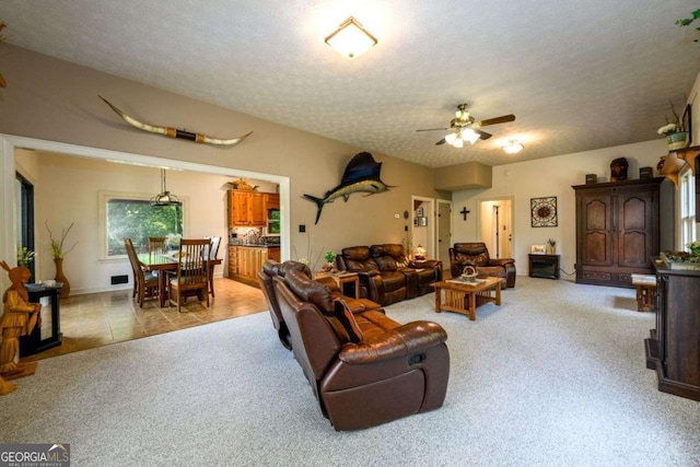 carpeted living room featuring ceiling fan and a textured ceiling