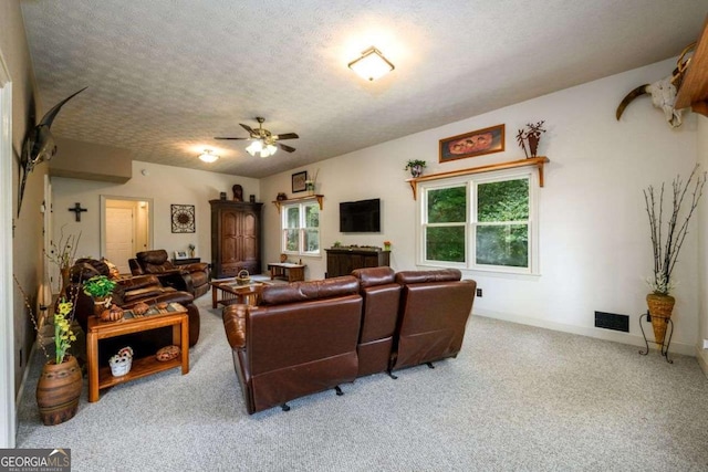 living room with ceiling fan, light colored carpet, and a textured ceiling