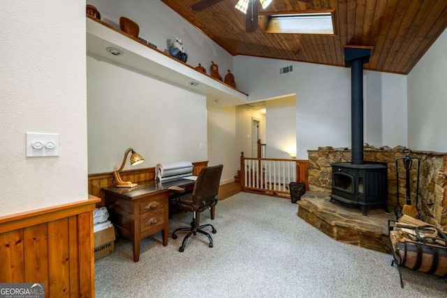 home office with lofted ceiling, ceiling fan, carpet, wooden ceiling, and a wood stove