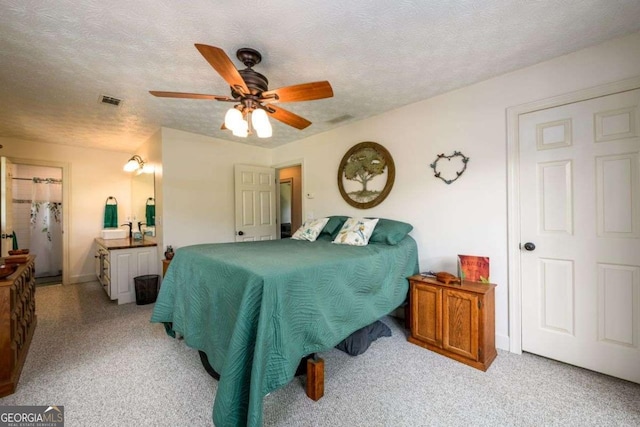 carpeted bedroom featuring ceiling fan and a textured ceiling