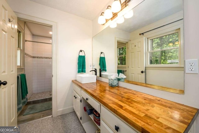 bathroom with an inviting chandelier, tiled shower, and vanity