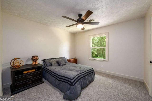 carpeted bedroom featuring ceiling fan and a textured ceiling