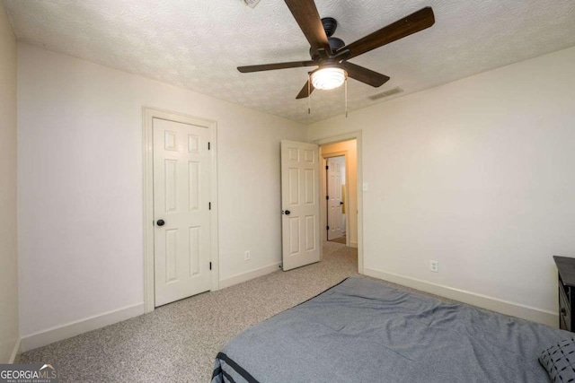 carpeted bedroom featuring ceiling fan and a textured ceiling