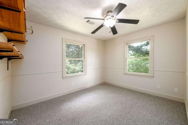 carpeted spare room with ceiling fan and a textured ceiling