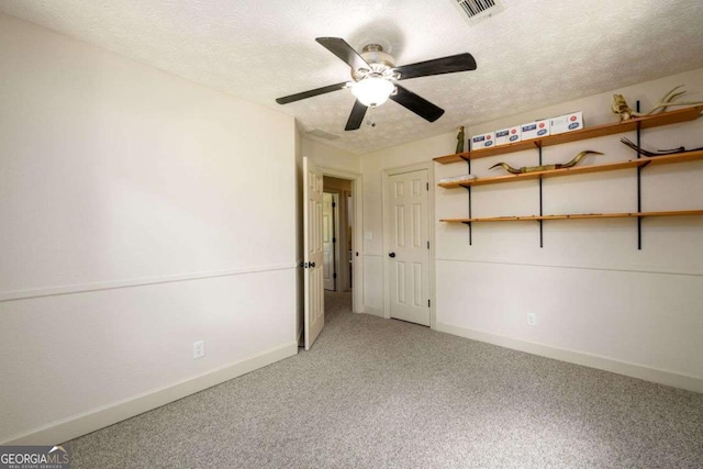 spare room featuring ceiling fan, carpet, and a textured ceiling