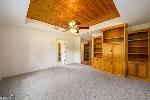 unfurnished living room with ceiling fan, a raised ceiling, light carpet, and wooden ceiling