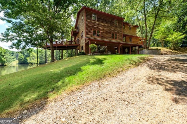 rear view of property with a deck with water view and a yard