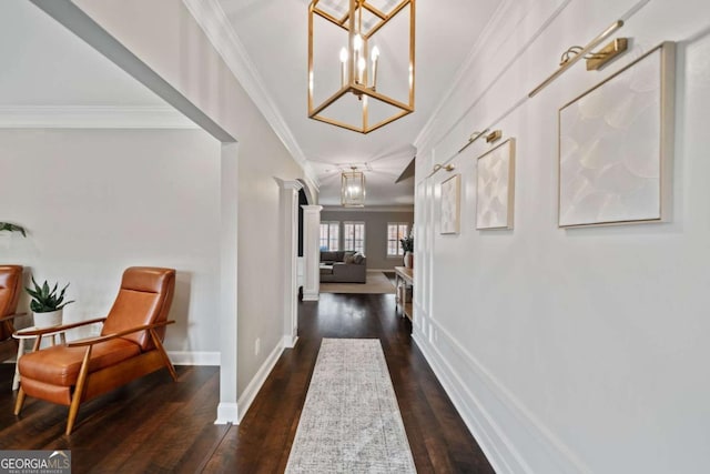 hall with crown molding, a notable chandelier, dark wood-type flooring, and ornate columns