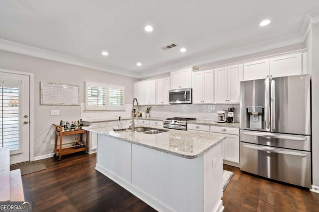 kitchen with sink, appliances with stainless steel finishes, light stone counters, an island with sink, and white cabinets