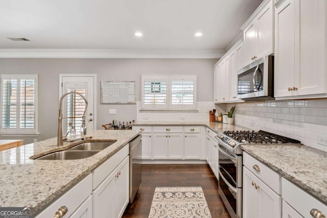 kitchen featuring stainless steel appliances, white cabinetry, light stone countertops, and sink