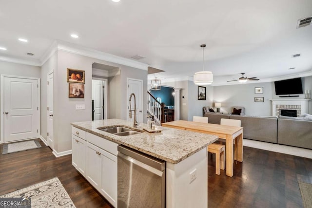 kitchen featuring decorative light fixtures, an island with sink, sink, white cabinets, and stainless steel dishwasher